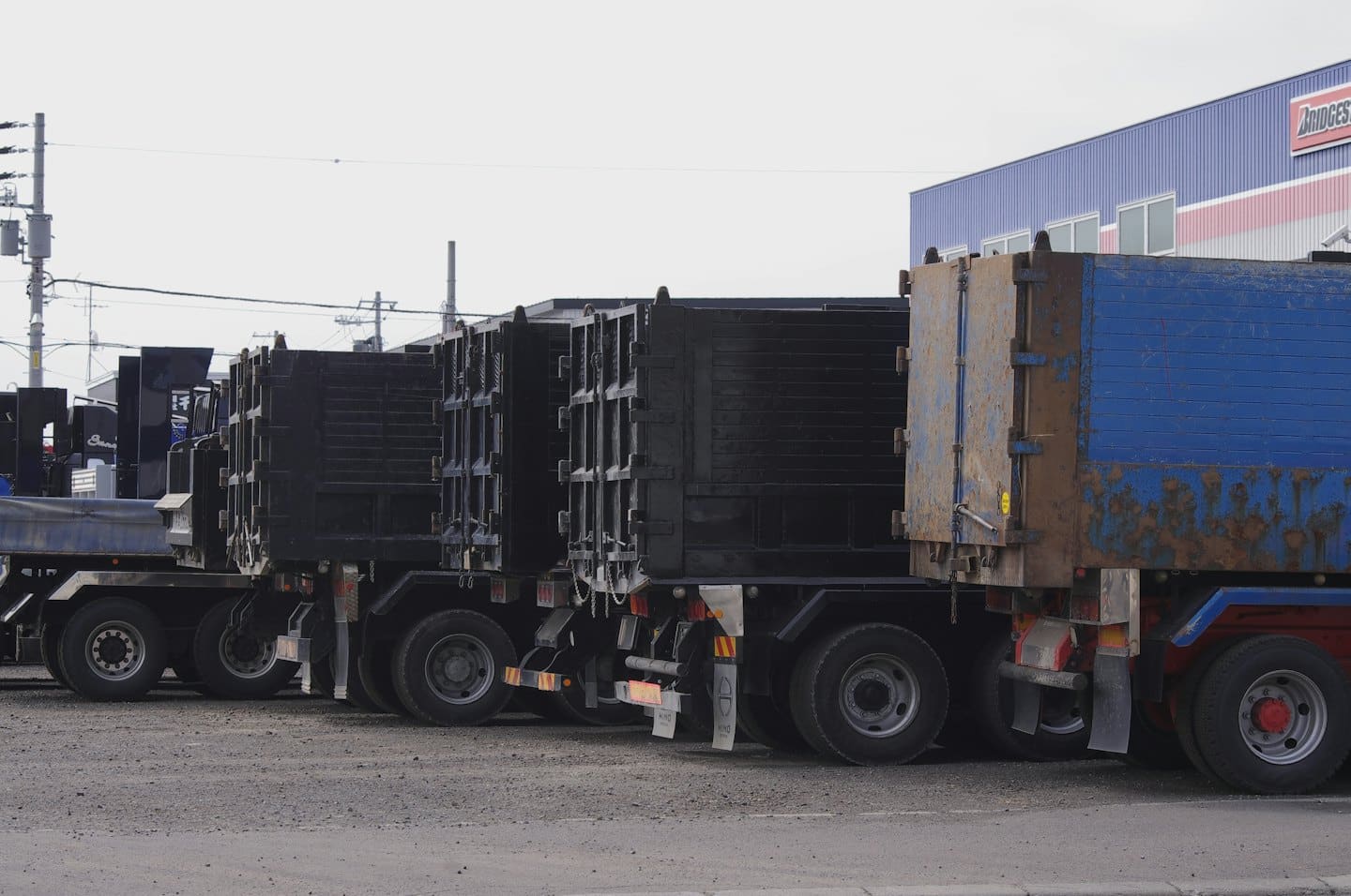 Heavy-duty dump trucks parked on a gravel lot.