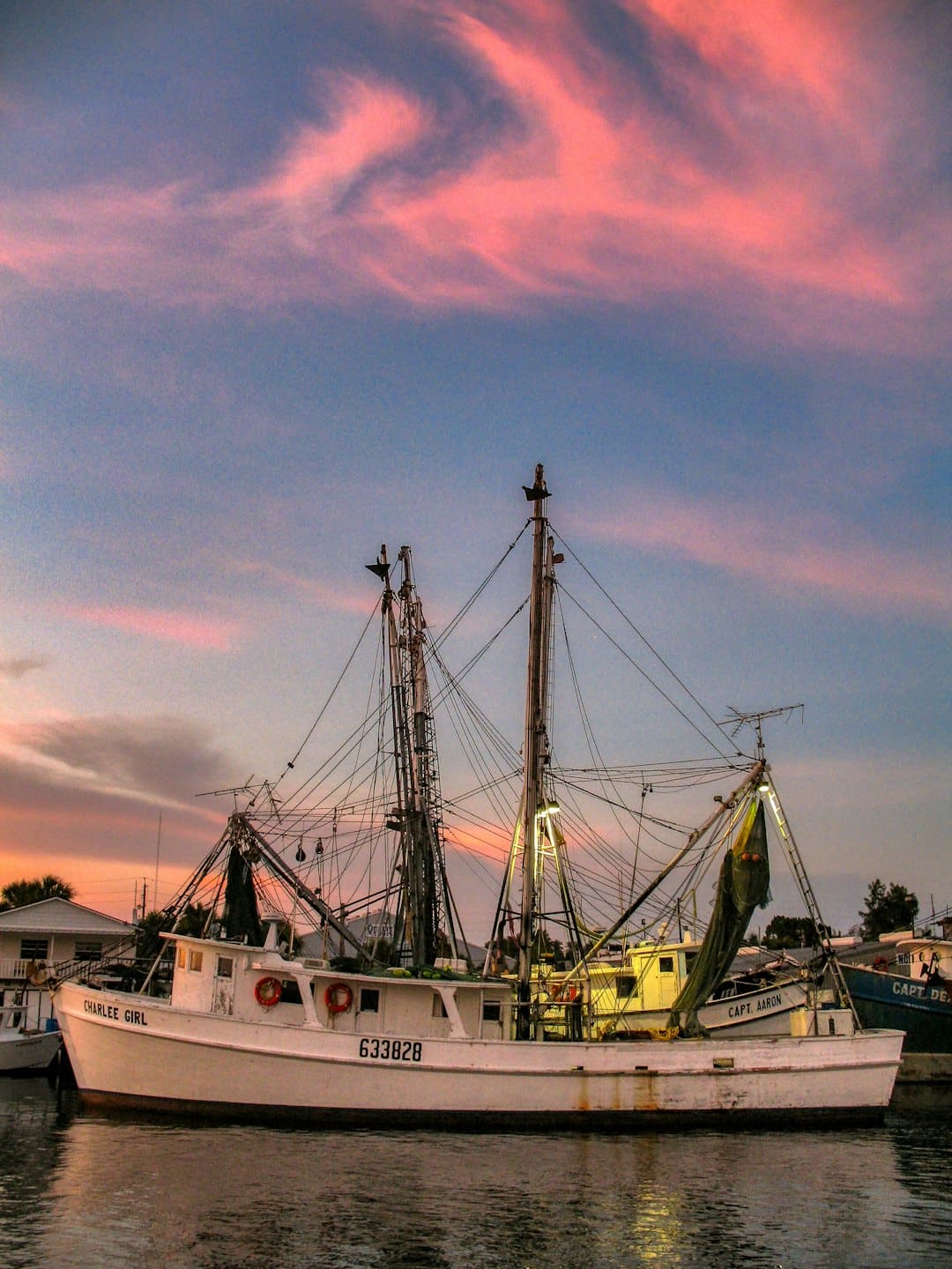 A fishing trawler sits moored in a calm harbor.
